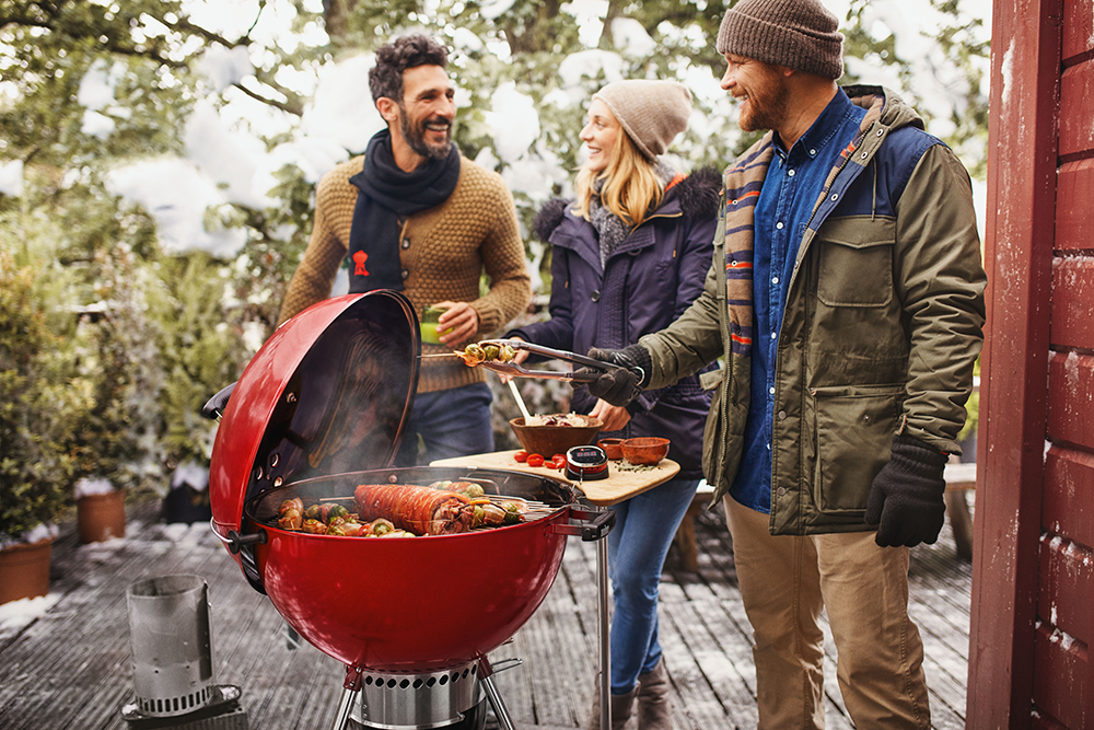A lifestyle shot with friends around a Weber BBQ.