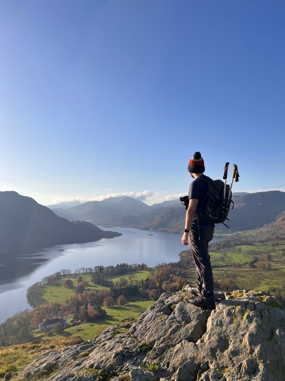 Martin stood on top of a craggy rock looking out towards Ullswater lake in the background.